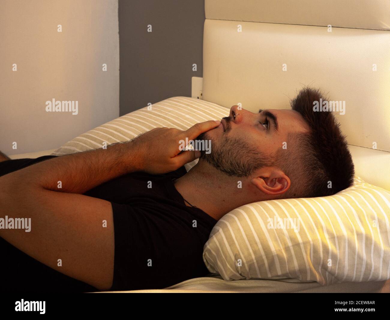 Joven hombre acostado en la cama pensando en su novia eso está viviendo  lejos Fotografía de stock - Alamy