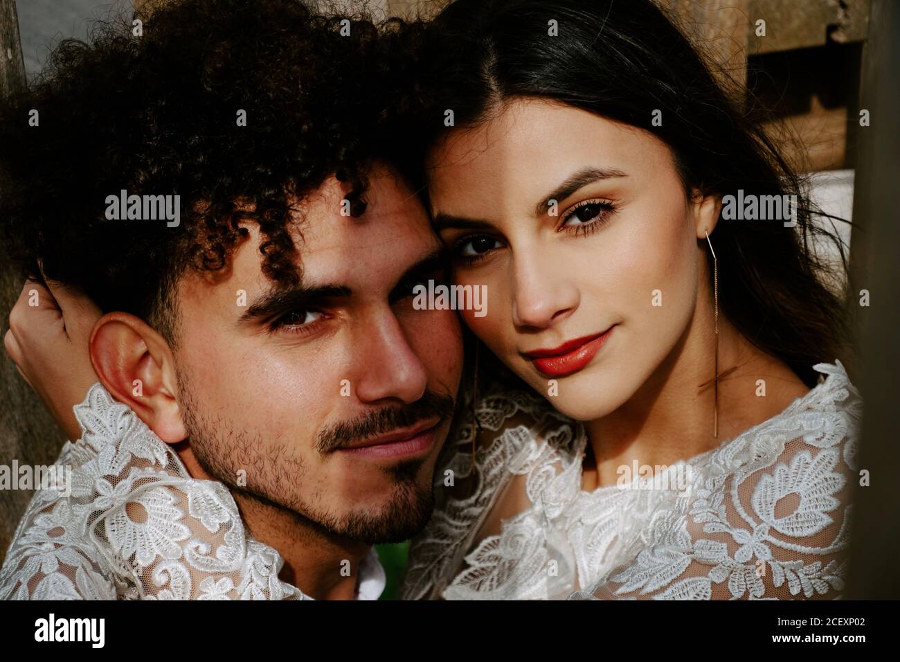 Gran ángulo de sensuales parejas recién vestidas en elegante ropa que se cuddling suavemente mientras está de pie en un puente de madera mirando a la cámara Fotografía de stock - Alamy Gran ángulo de sensuales parejas recién vestidas en elegante ropa que se cuddling suavemente mientras está de pie en un puente de madera mirando a la cámara Fotografía de stock - Alamy