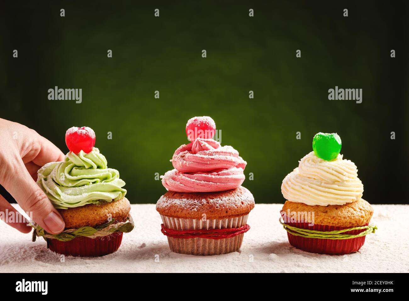 Cosecha persona anónima tomando deliciosa cupcake festiva casera con verde crema batida de color de la mesa Foto de stock