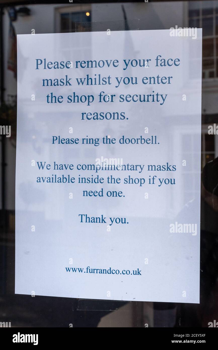Aviso en la puerta de una tienda de joyeros pidiendo a la gente que retire sus máscaras por razones de seguridad durante la pandemia de covid-19 coronavirus, 2020 Foto de stock