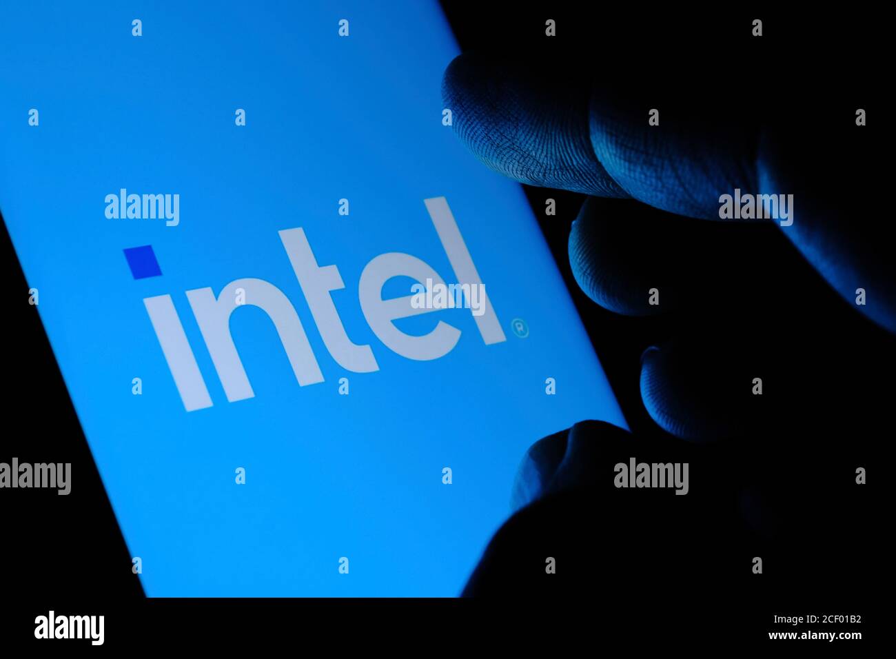 Nuevo logotipo de Intel visto en la pantalla y la punta del dedo borrosa tocándolo en una oscuridad. Intel presentó su logotipo de nueva Marca Foto de stock
