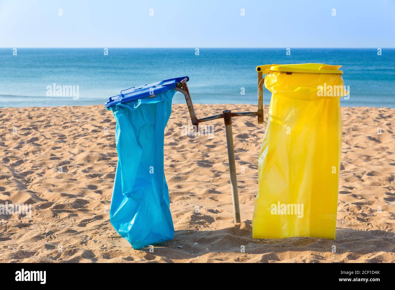 Bolsas de basura vacías en la playa de arena portuguesa con el mar azul Foto de stock