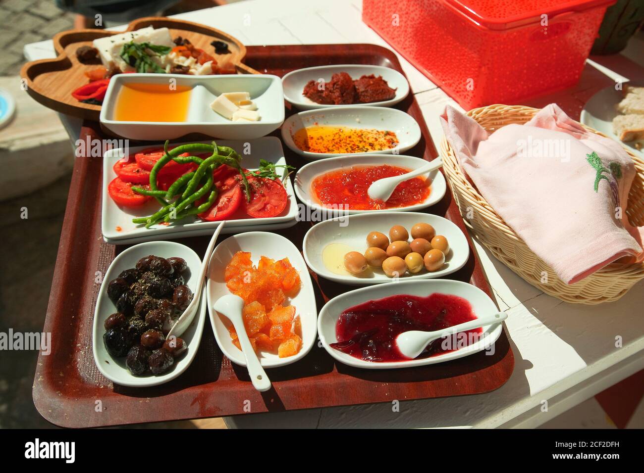 Desayuno turco tradicional con aceitunas, mermelada, miel, mermelada, frutas, queso, mantequilla, tomates y pimientos listos para servir en un restaurante en el Foto de stock
