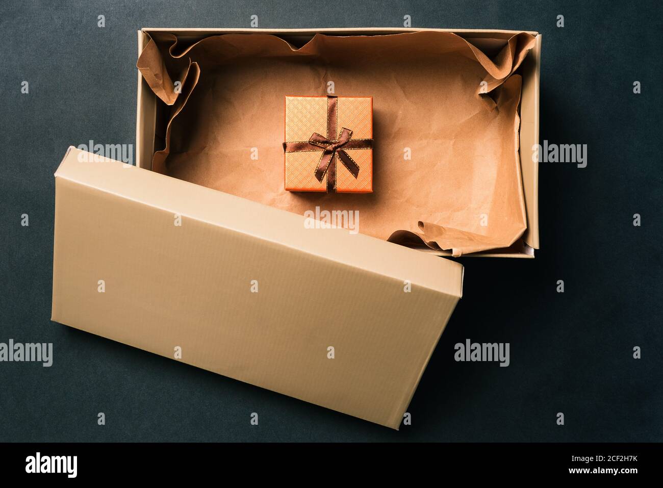 Abrir caja de cartón y regalo sobre un fondo oscuro. Caja de regalo con un  arco dentro de la caja. Sorpresa para unas vacaciones, cumpleaños y  aniversario Fotografía de stock - Alamy
