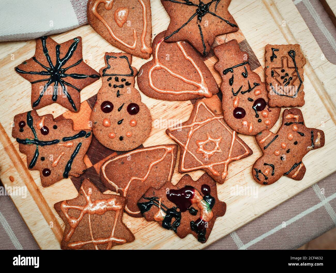 Los niños han decorado a mano galletas de jengibre de Navidad figurines en el tablero de la cocina Foto de stock