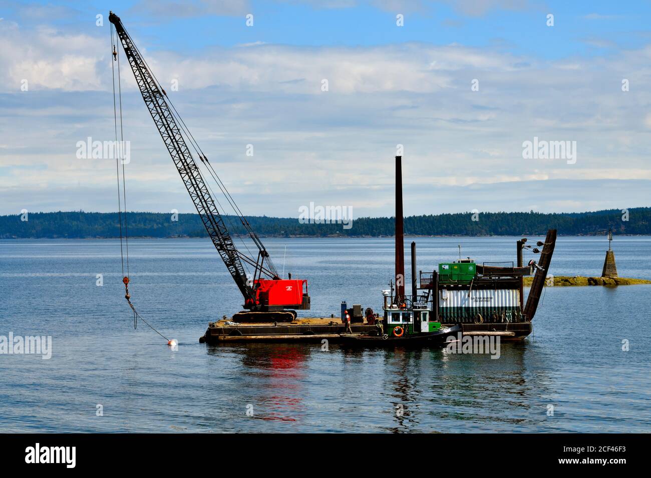 Una grúa colocada en una barcaza flotante para trabajar en el canal Stuart en Vancouver Islkand British Columbia Canada. Foto de stock