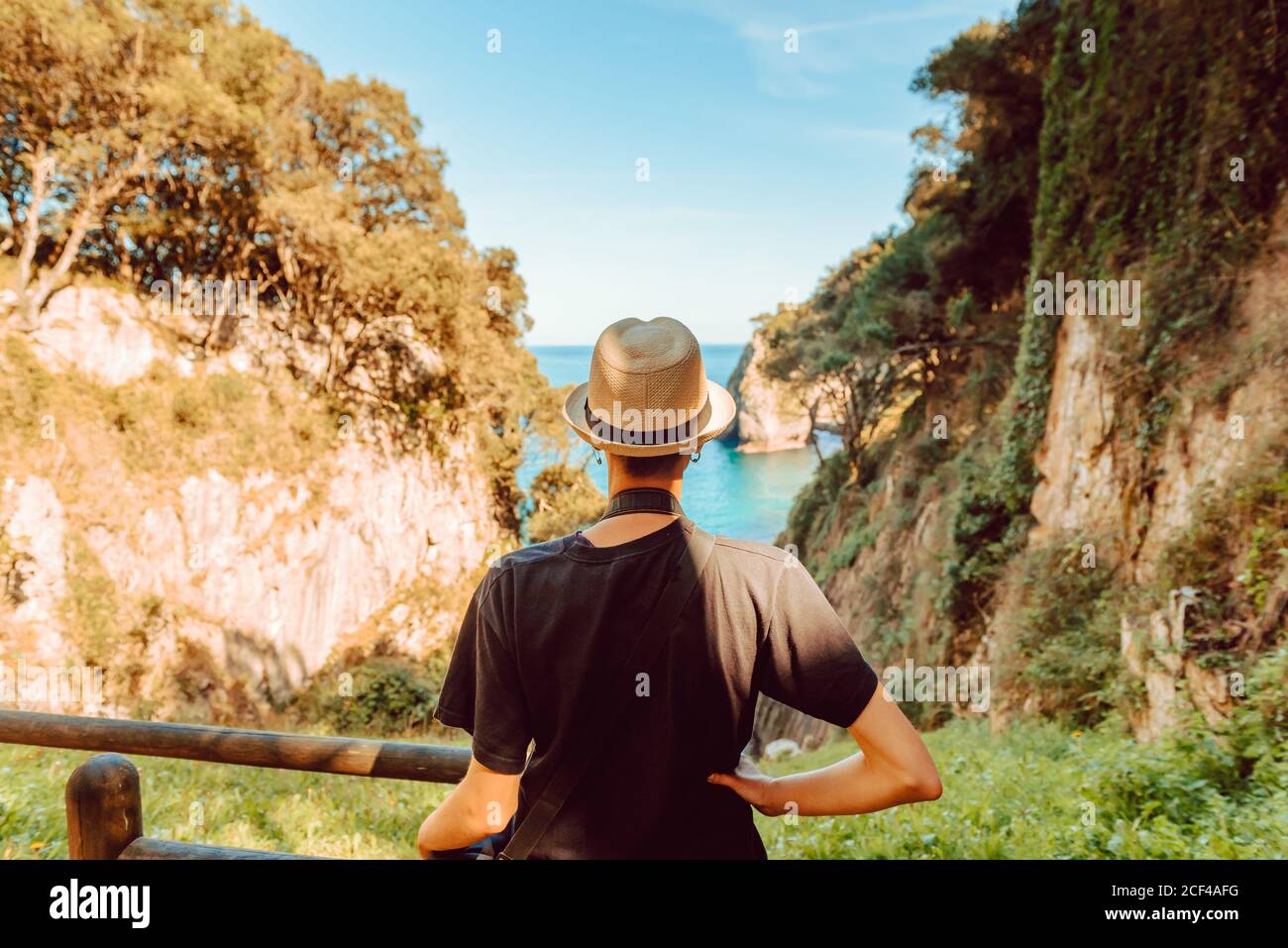 Vista trasera de mujer en sombrero junto a barandilla de madera y  disfrutando de una vista impresionante del mar y los acantilados en  Ribadedeva Asturias España Fotografía de stock - Alamy