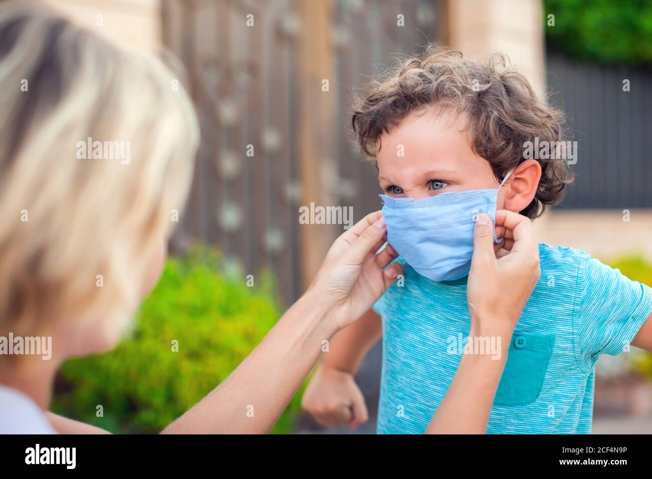 Padre con niño en máscara al aire libre. Madre ayudando a un niño enojado a  usar mascarilla durante el brote de coronavirus y gripe. Protección contra  virus y enfermedades Fotografía de stock -