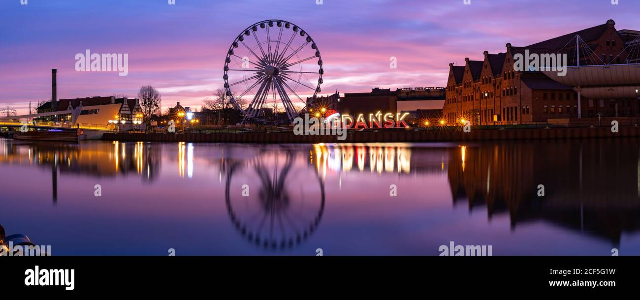 Panorama del río Motlawa y la noria con reflejo de agua en el casco antiguo de Gdansk por la noche, Polonia Foto de stock