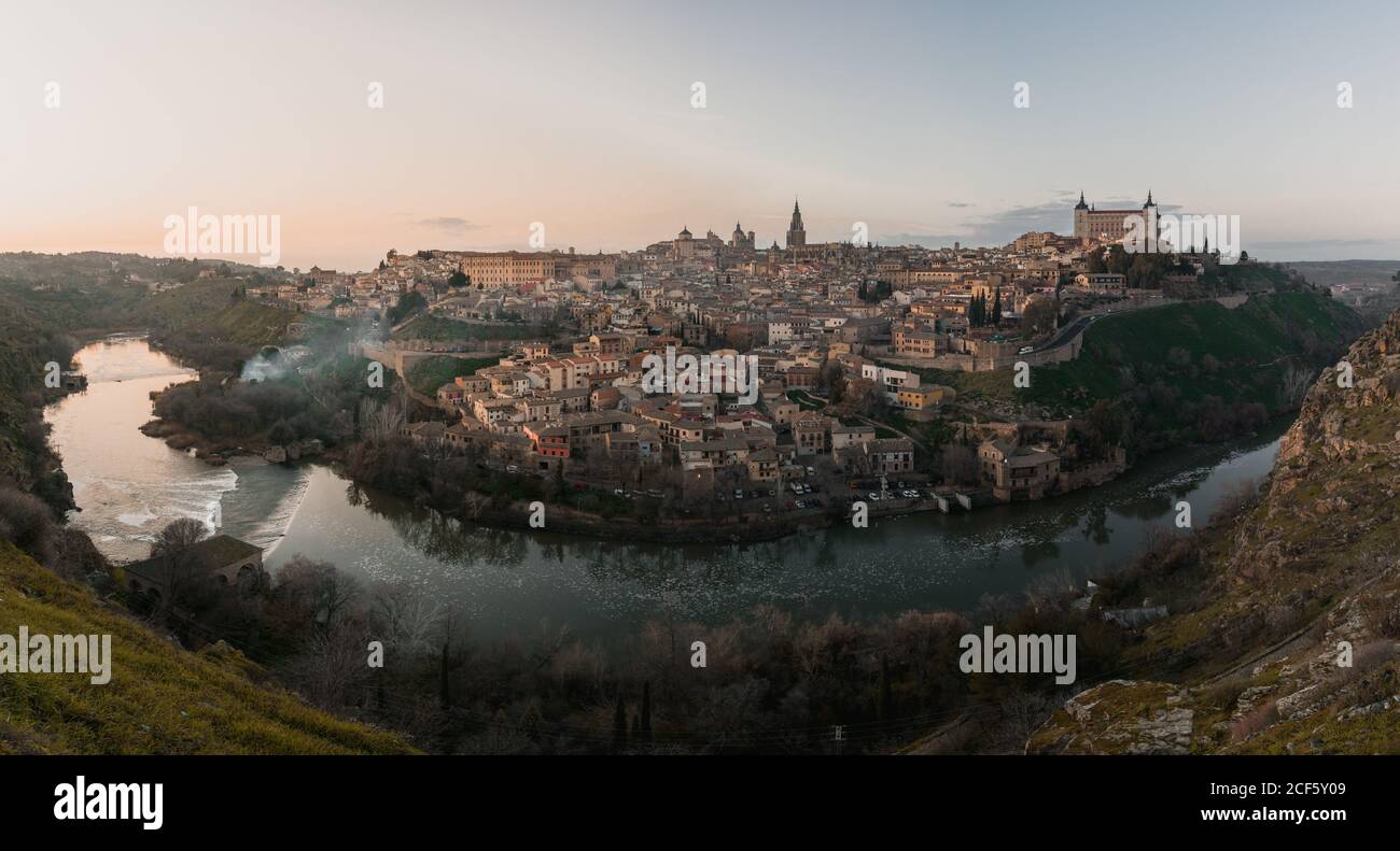 Vista panorámica sobre el río de la ciudad vieja de Toledo en España con castillos medievales y fortalezas al atardecer con nublado cielo y reflexión en el agua del río Foto de stock