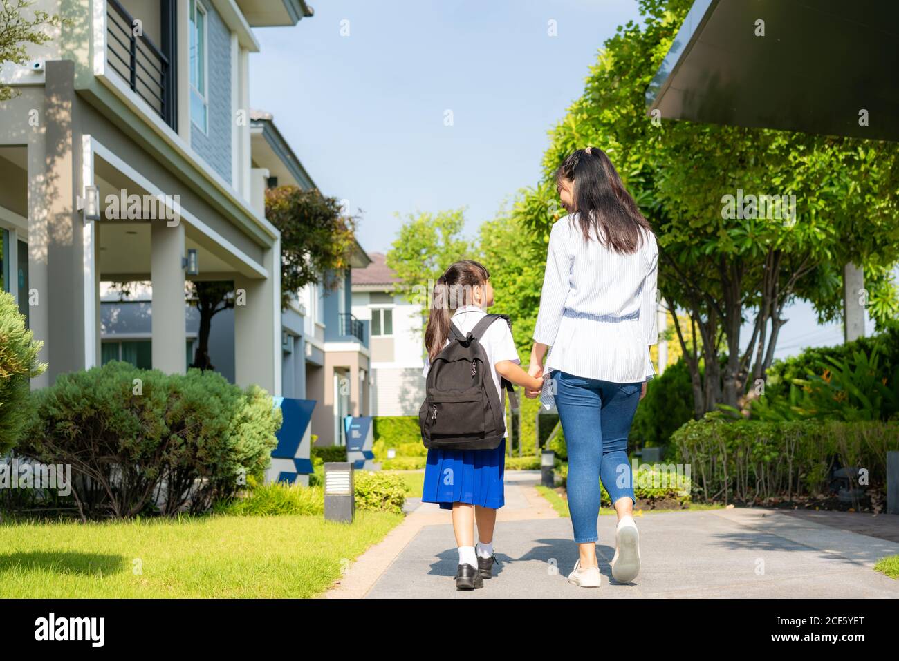 Feliz madre asiática e hija estudiante de escuela primaria caminando a la escuela en la rutina de la mañana para el día en la vida preparándose para la escuela. Foto de stock