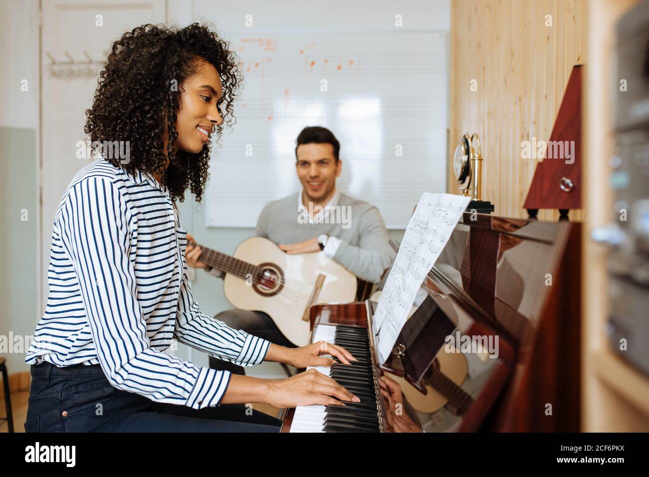 Vista lateral de una joven mujer negra tocando el piano cerca de un hombre  tocando la guitarra en un estudio de música Fotografía de stock - Alamy