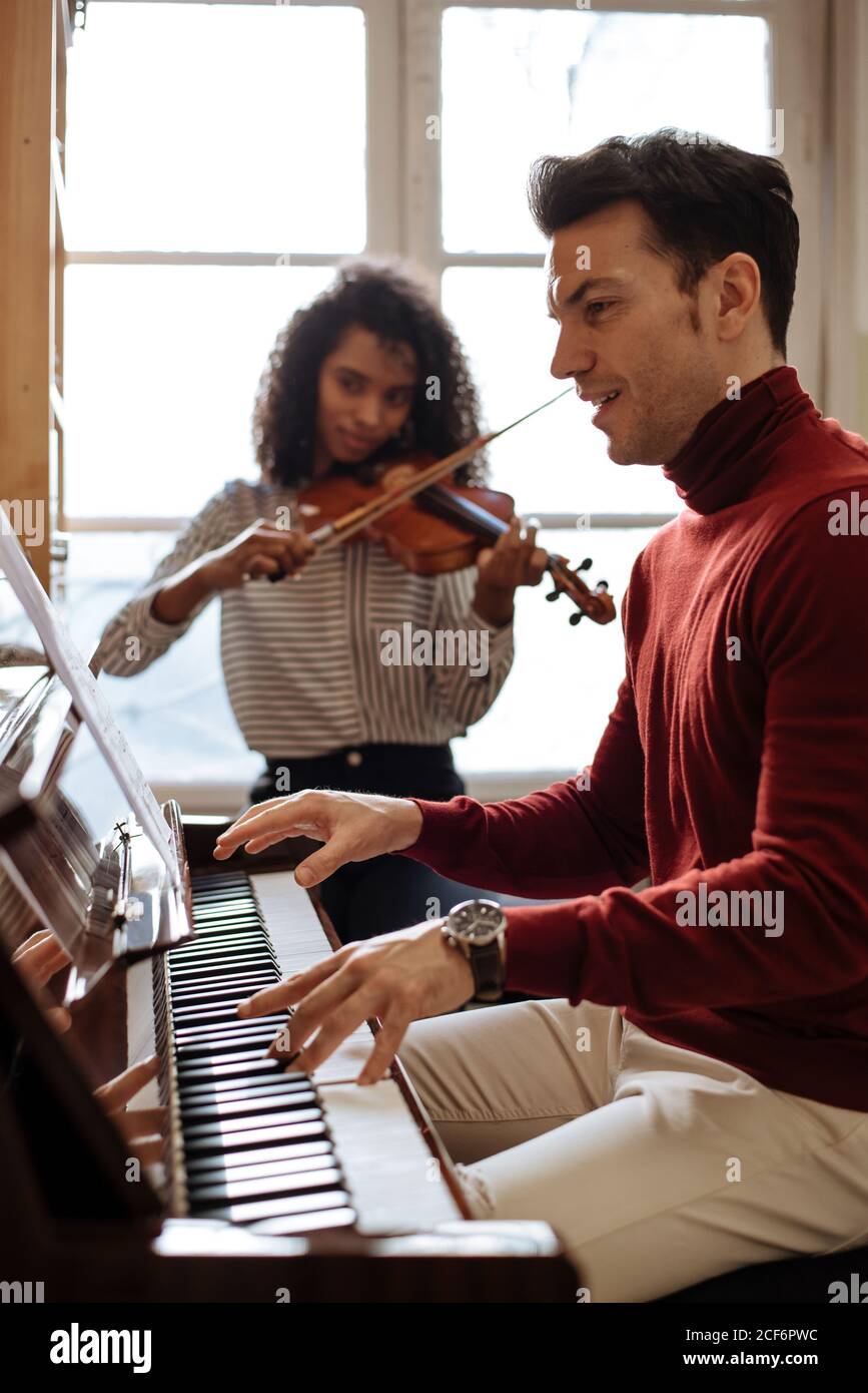 Vista lateral de un joven tocando el piano cerca de una mujer negra tocando  el violín en un estudio de música Fotografía de stock - Alamy