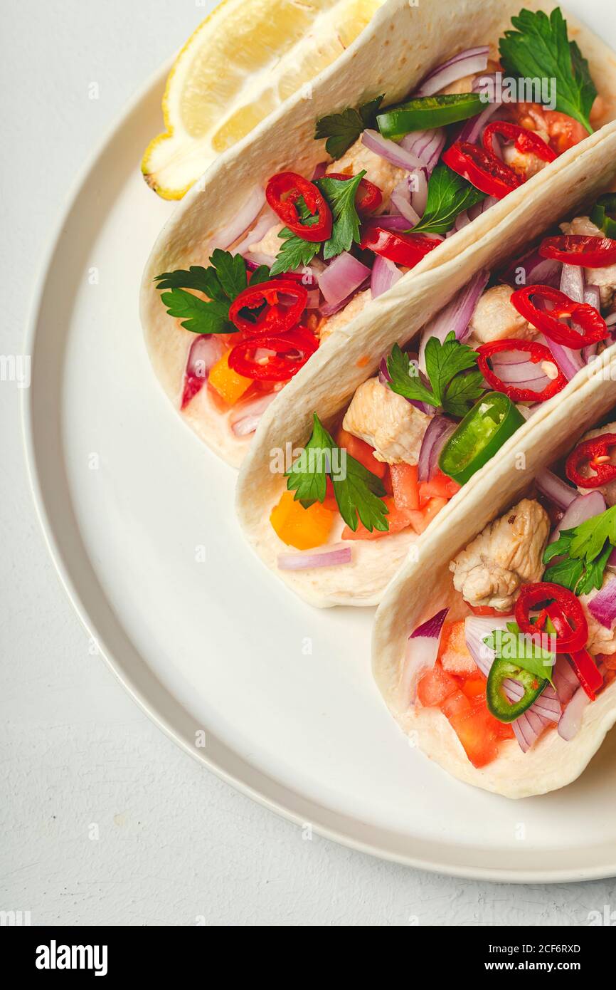 Tacos mexicanos caseros con verduras frescas y pollo sobre fondo blanco