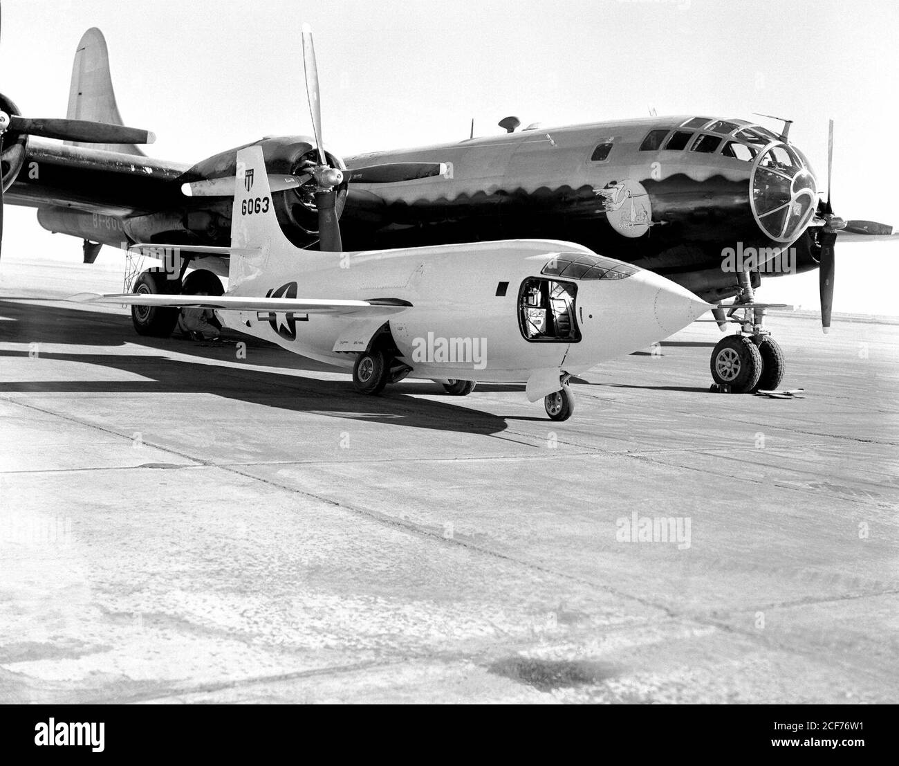 El Bell Aircraft Corporation X-1-2 sentado en la rampa de la Estación de Investigación de Vuelo de Alta velocidad NACA con el buque de lanzamiento Boeing B-29 detrás. El B-29 fue cariñosamente referido como "mirto fértil". La pintura cerca de la nariz representa una cigüeña que lleva un mazo que es simbólico de la nave madre que lanza su bebé (X-1-2). La puerta de acceso del piloto está abierta a la cabina del avión X-1-2. Foto de stock