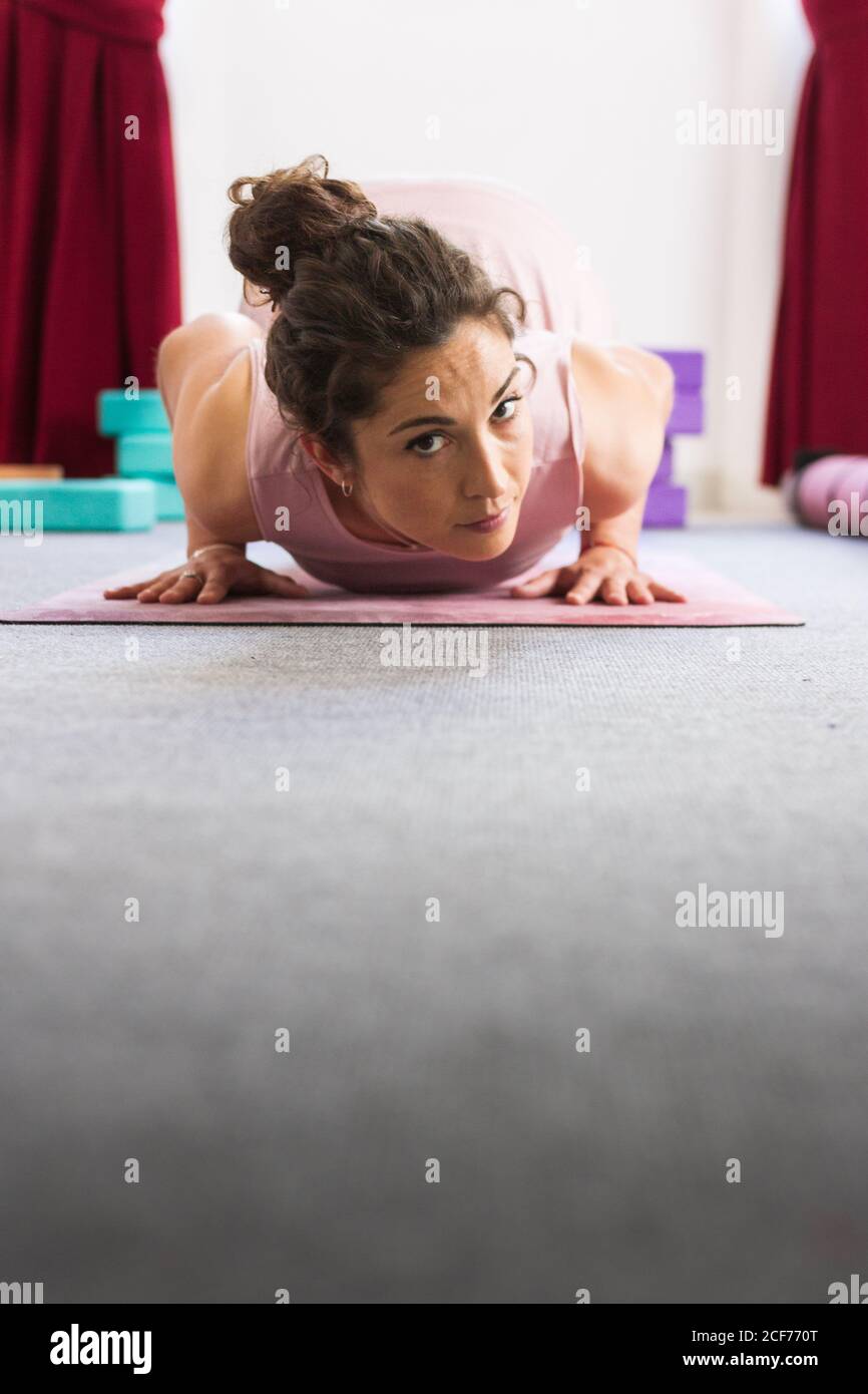Vista lateral de la morena concentrada deportiva flexible en la práctica de sportswear acostarse yoga pose sobre la alfombra Foto de stock