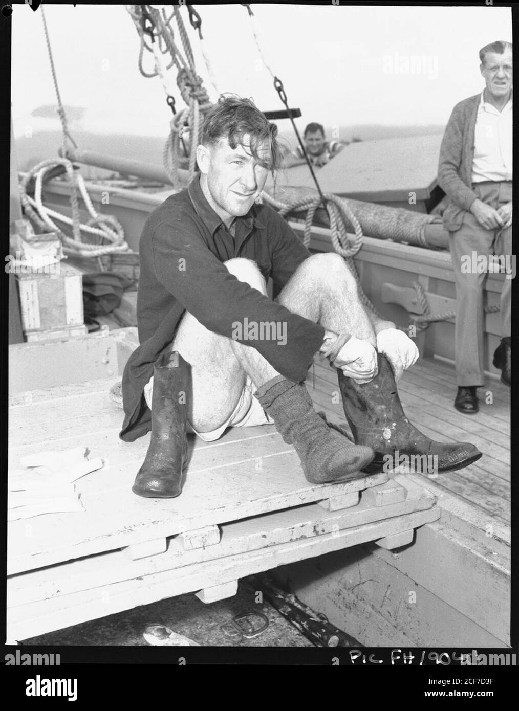 Hombre sentado en cubierta poniendo botas] [Frank Hurley] Fotografía de  stock - Alamy