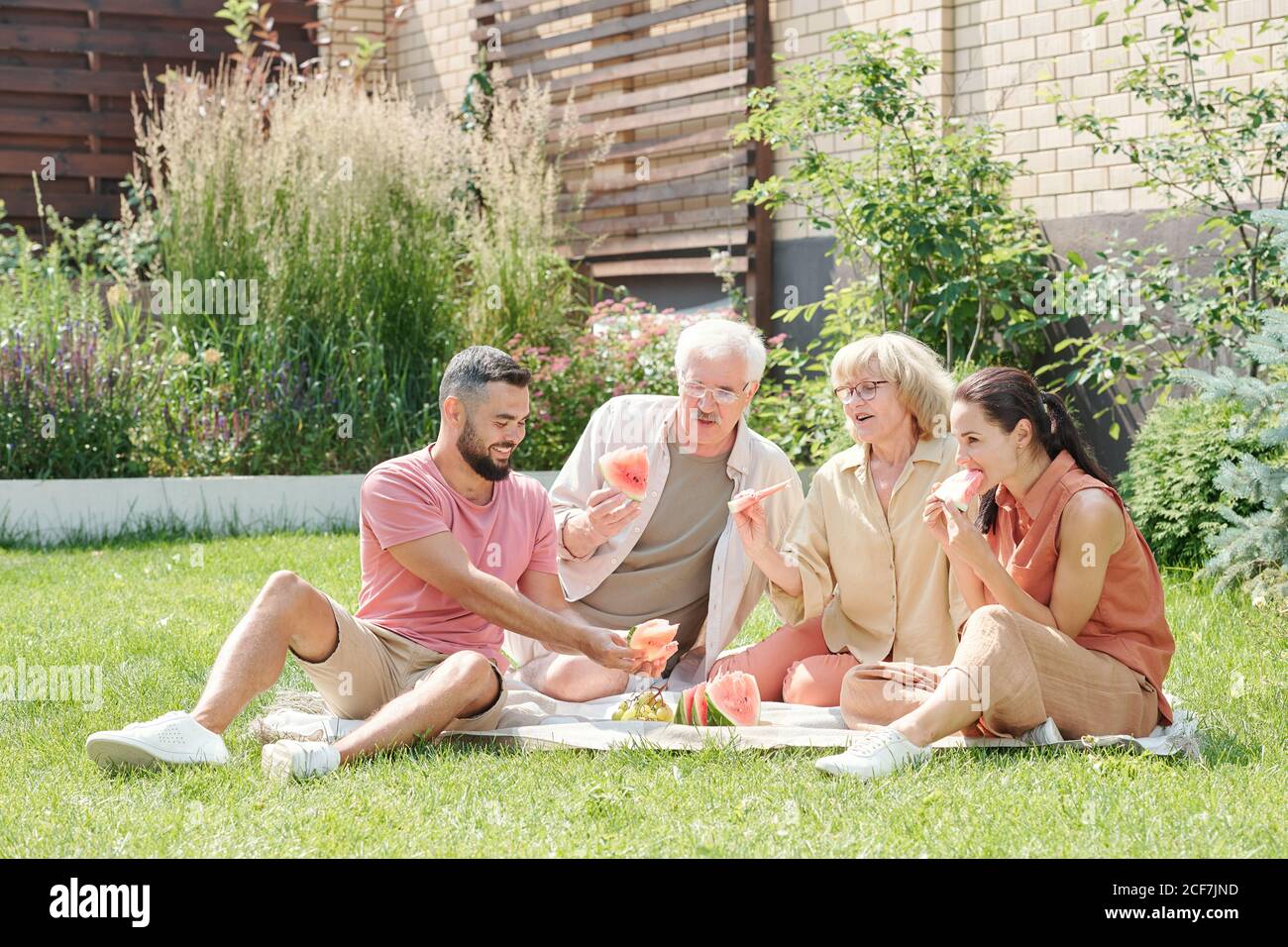 Foto familiar de un hombre y una mujer de edad avanzada que se va a hacer un picnic con sus hijos mayores en el césped, espacio de copia Foto de stock
