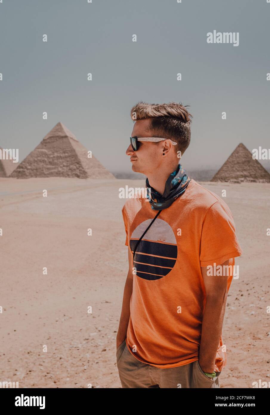 Hombre hombre seguro de viaje con gafas de sol mirando mientras se  encuentra en el desierto contra las famosas grandes pirámides de el Cairo,  Egipto Fotografía de stock - Alamy