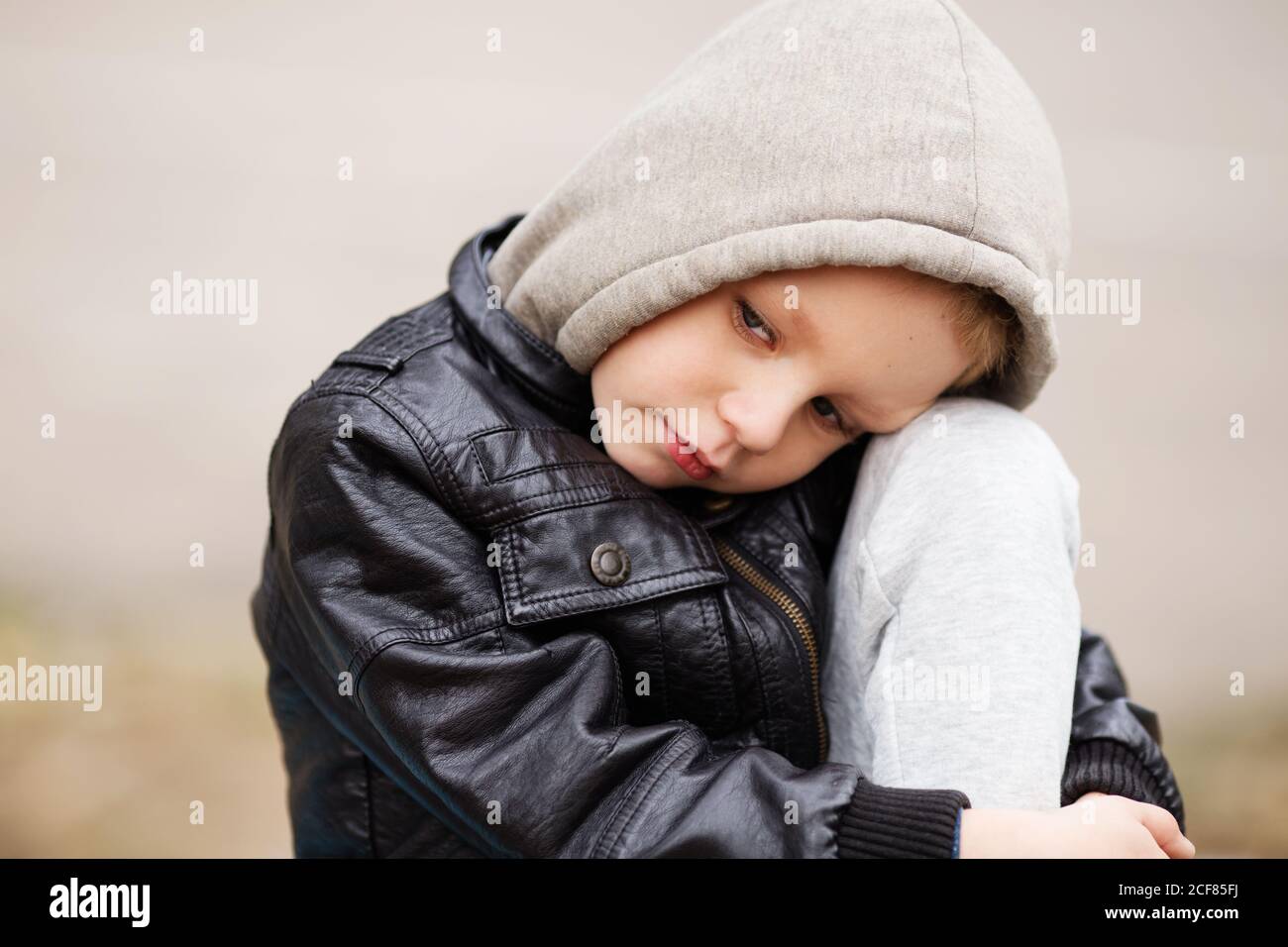 Niño ofendido. Retrato de niño triste con chaqueta de cuero negro y sudadera  con capucha al aire libre. Niños urbanos Fotografía de stock - Alamy
