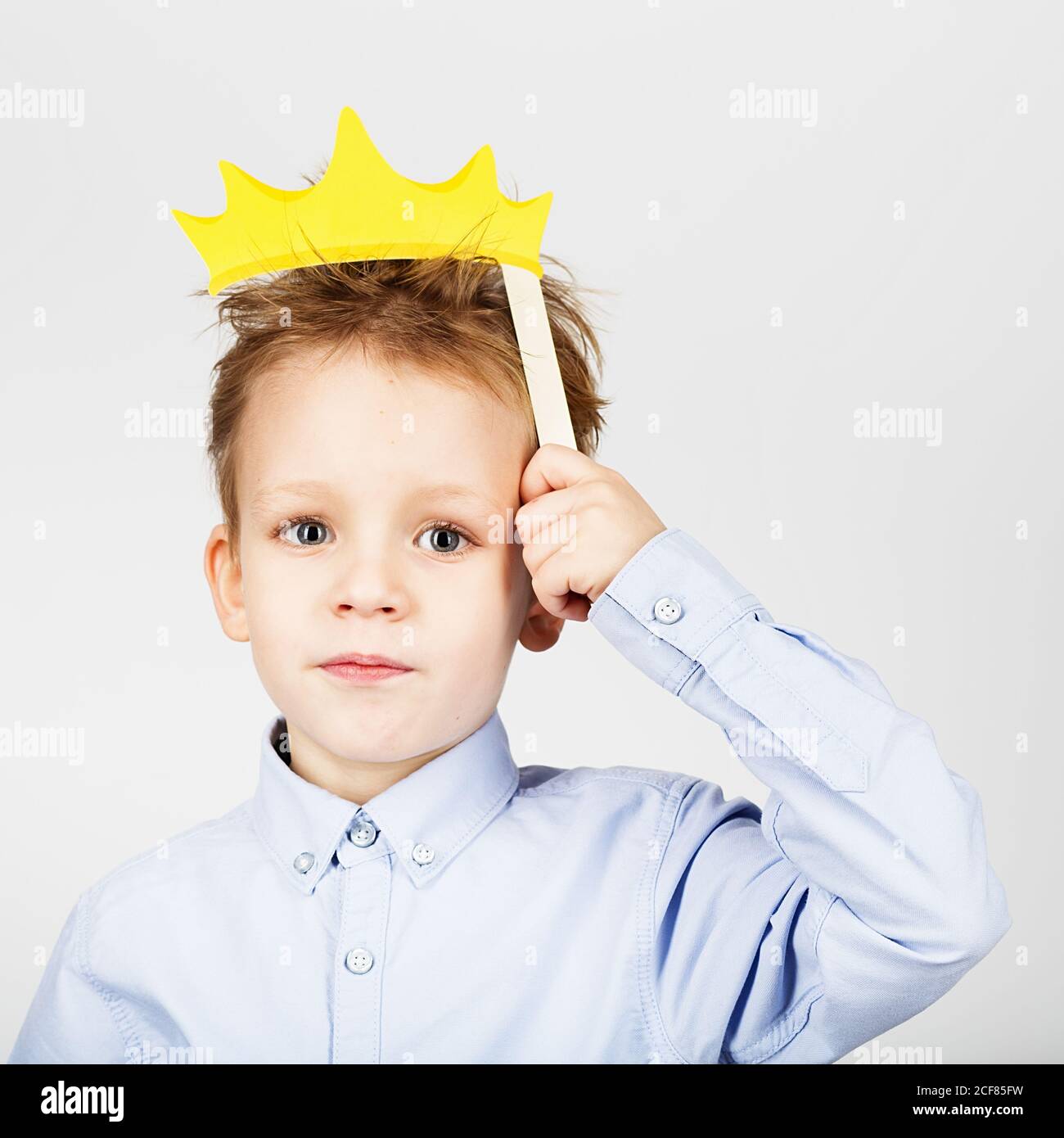 Retrato de un lindo niño con corona de papel amarilla sobre fondo blanco.  Alegre y sonriente Kid con divertidos accesorios fotográficos. De vuelta a  la escuela Fotografía de stock - Alamy