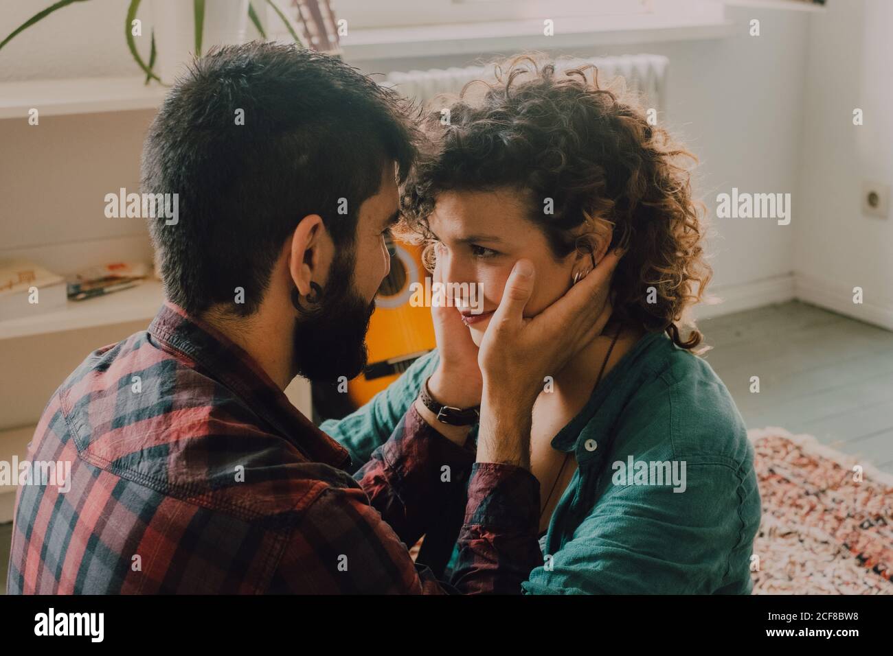 Vista lateral de la pareja tierna en ropa informal que se cuddling y