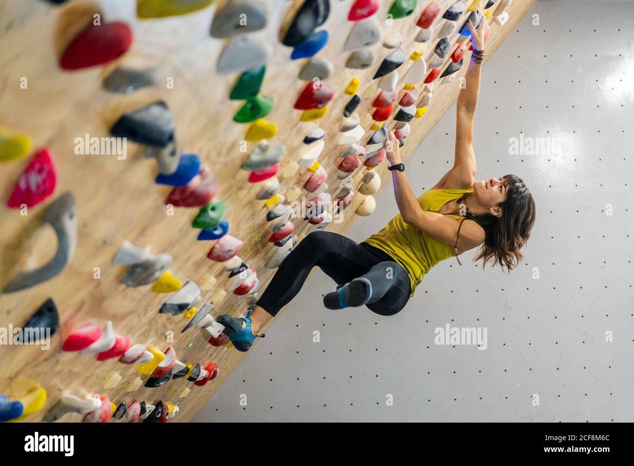 Vista lateral desde abajo de mujer enfocada en ropa deportiva colgando en  una pared empinada sobre las alfombras en un moderno centro de escalada  Fotografía de stock - Alamy