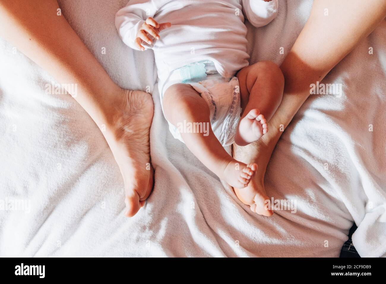 Vista superior del recién nacido de cosecha en el pañal tumbado cama con madre en casa Foto de stock