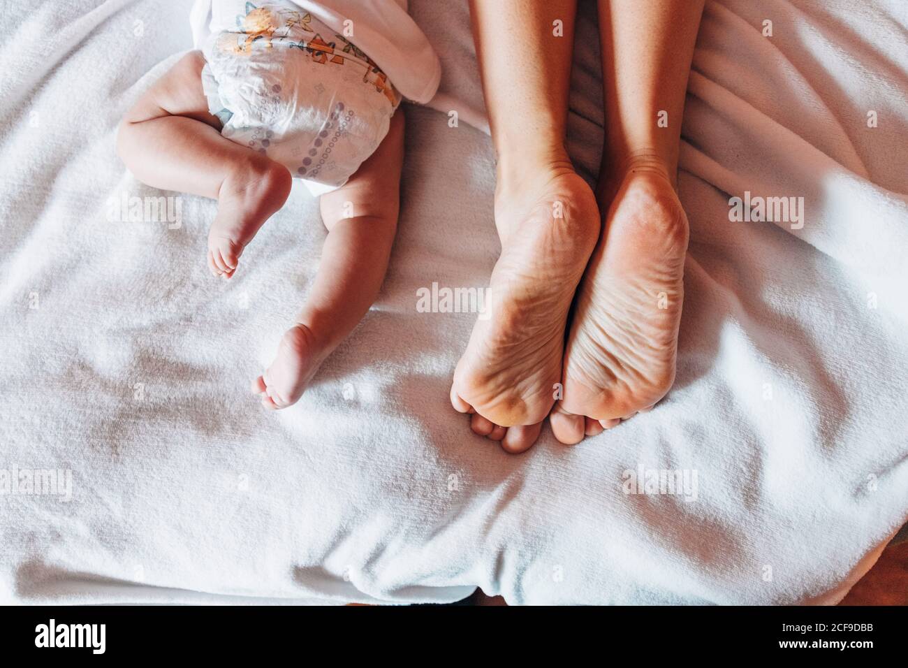 Vista superior del recién nacido de cosecha en el pañal tumbado cama con madre en casa Foto de stock