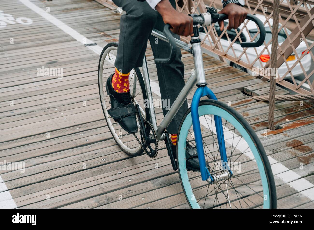 Recortada anónimo bien vestido hombre de negocios ciclista en montar en bicicleta Camino de madera entre la estructura de metal rojo con en Nueva York ciudad Foto de stock