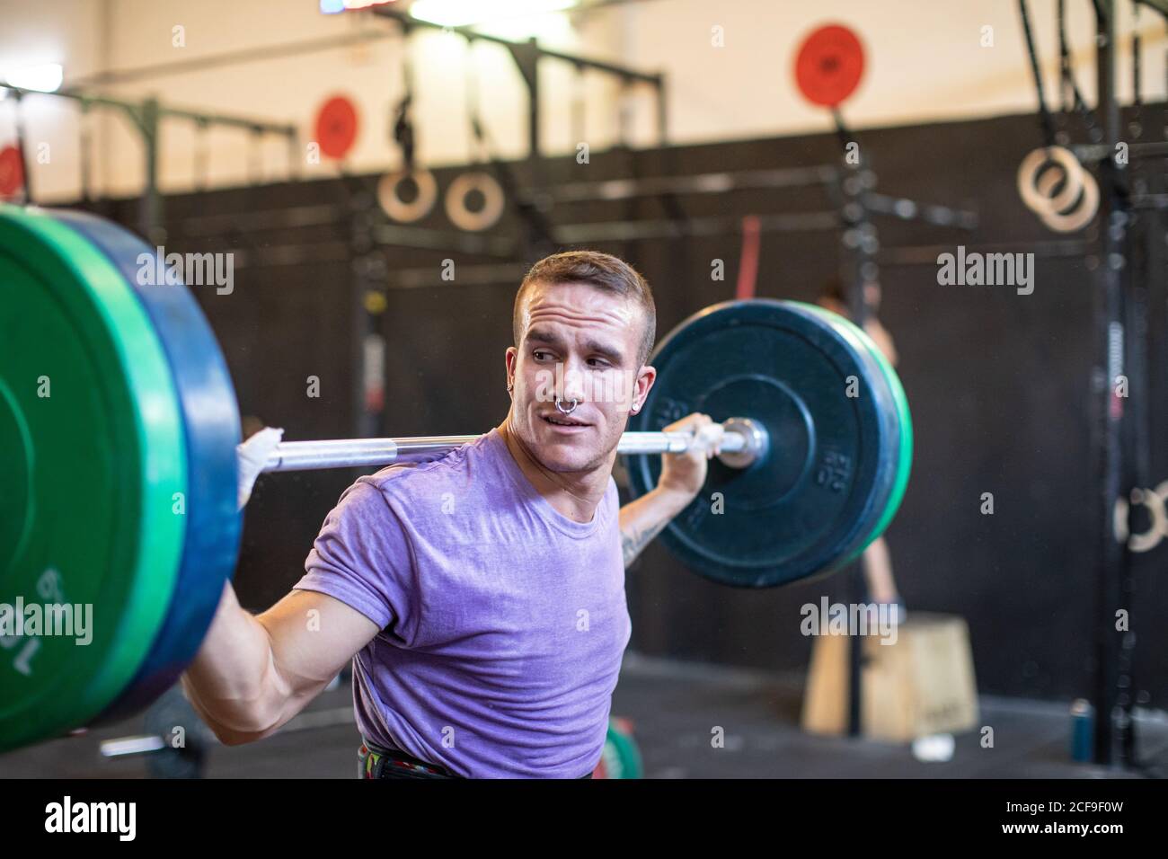 Un hombre guapo está ejercitando el pecho con barra en un gimnasio moderno