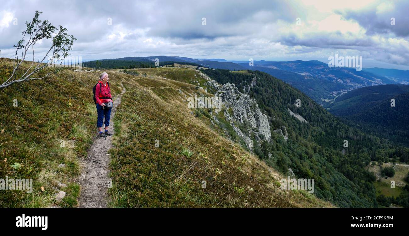 Mujer hiker en rojo sobre la cresta rocosa en Hohneck, por encima de Munster, Vosgos, Francia Foto de stock