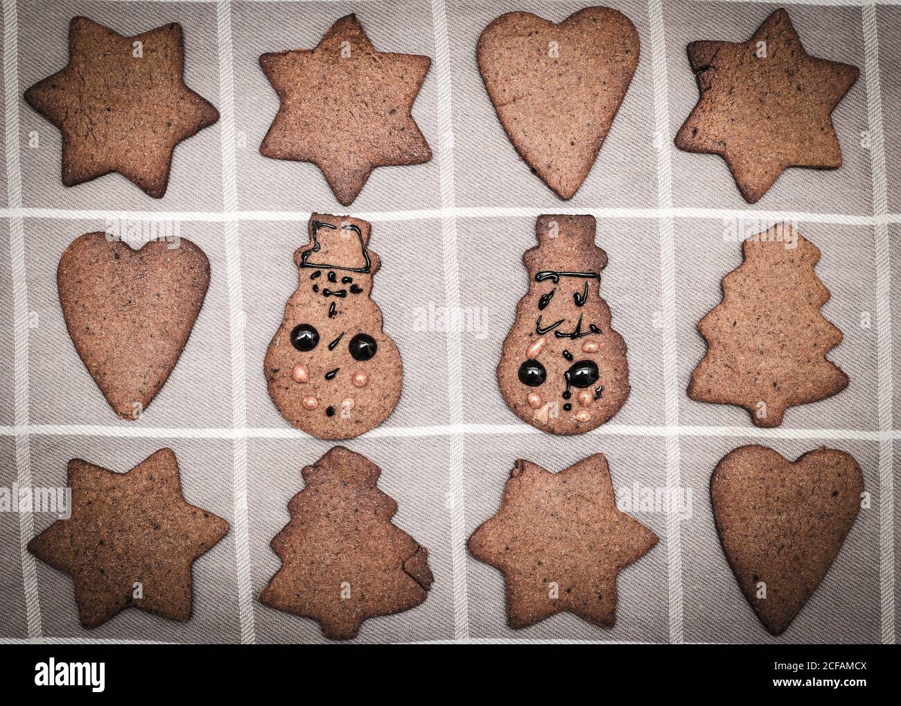 Mano adornado por los niños de Navidad pan de jengibre galleta de muñeco de nieve figurillas amidas otras galletas no decoradas Foto de stock