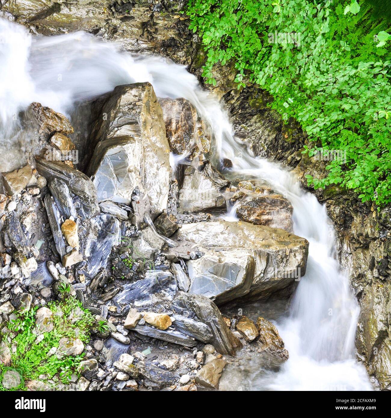 Reflejo de una imagen de cascada escénica, que se separa de la grieta entre enormes rocas Foto de stock