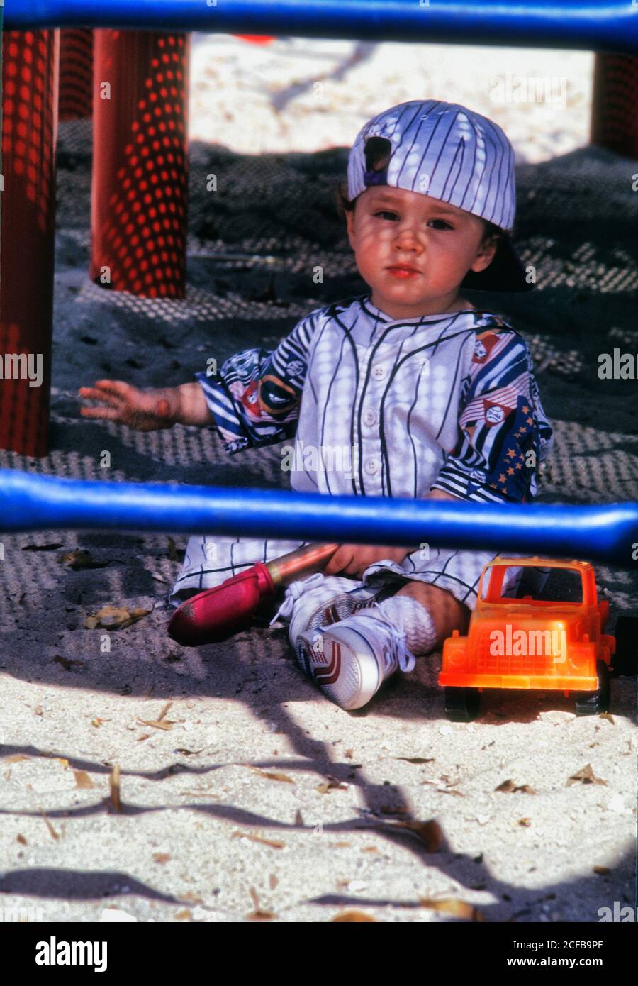 Niño pequeño jugando en arena con camión de juguete Foto de stock