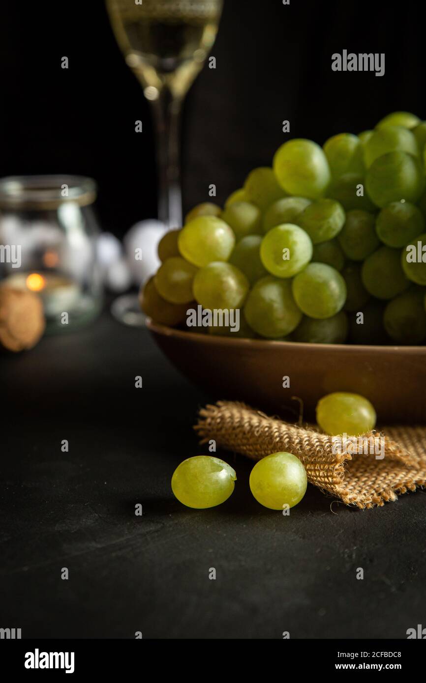 Celebración de Nochevieja con copas de vino con champán y colza uvas verdes  en la mesa decoradas con velas de té y blanco garland sobre fondo negro  Fotografía de stock - Alamy