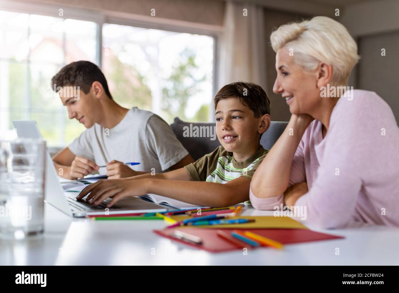 Madre ayudando a sus hijos a hacer la tarea en casa Foto de stock