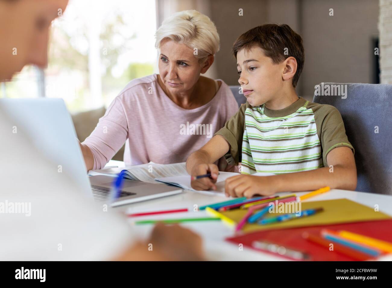 Madre ayudando a sus hijos a hacer la tarea en casa Foto de stock