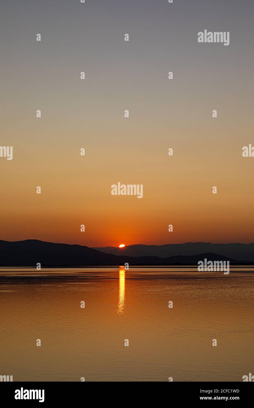 Colores intensos de una puesta de sol con reflejos en el agua Foto de stock