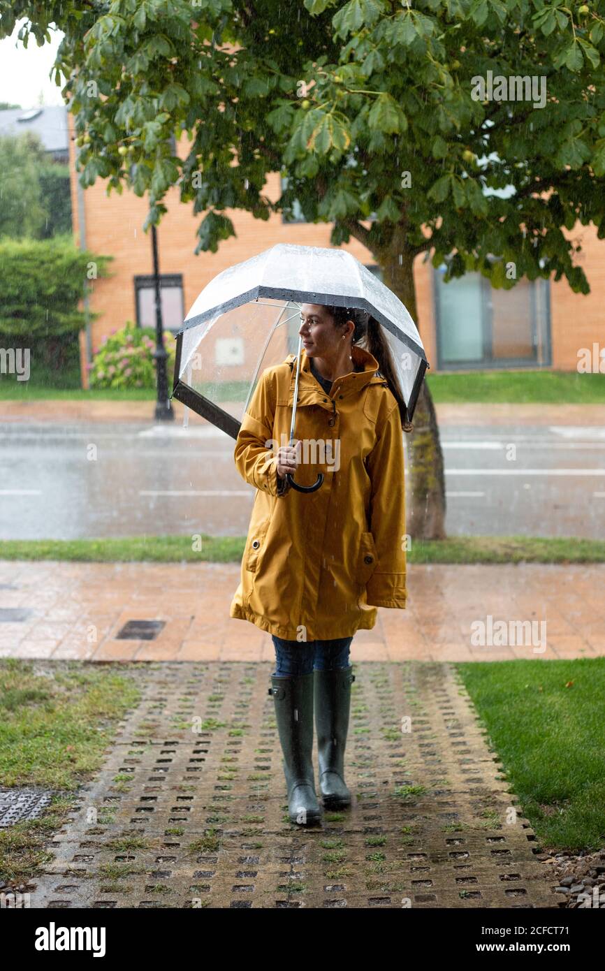 Una joven con chubasquero amarillo y paraguas se está divirtiendo mientras  camina por la ciudad en un ambiente tranquilo bajo la lluvia. Paseo,  lluvia, ciudad Fotografía de stock - Alamy