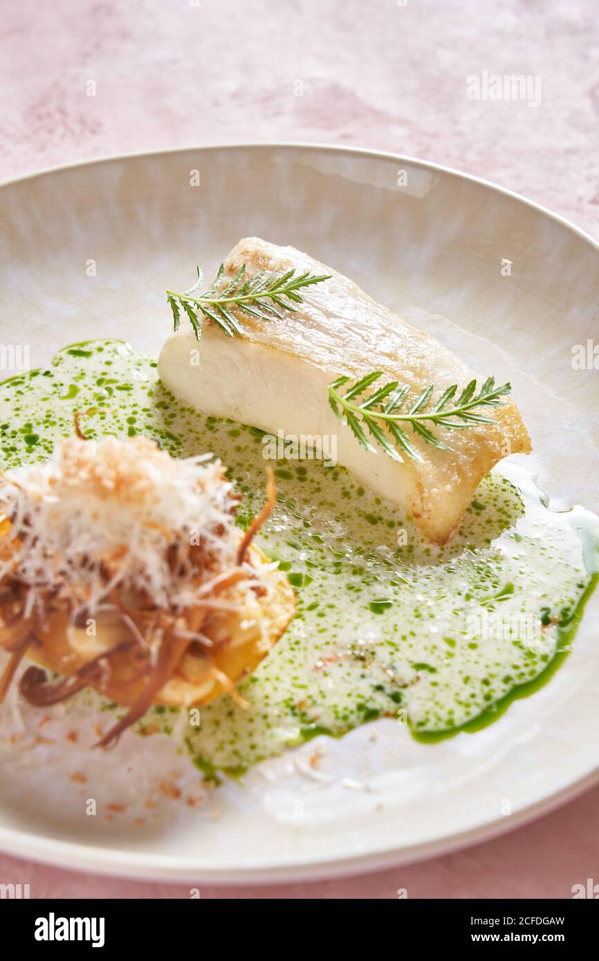 Salsa de crema a plato de pescado delicioso con hierba sobre rosa fondo en el restaurante Foto de stock