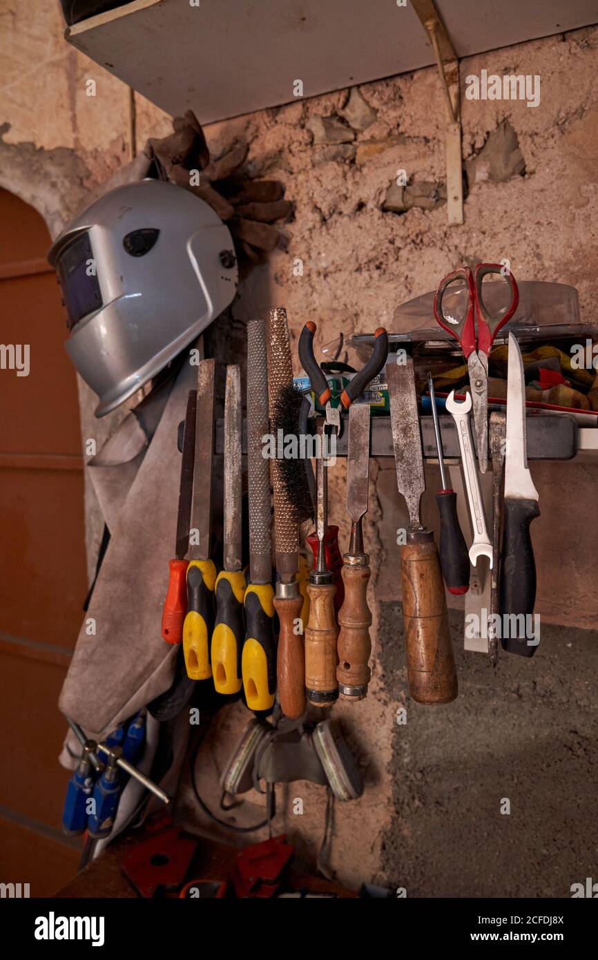 Juego de herramientas de trabajo y ropa protectora para soldar y. soldadura  colgando en la pared de escamas del taller Fotografía de stock - Alamy