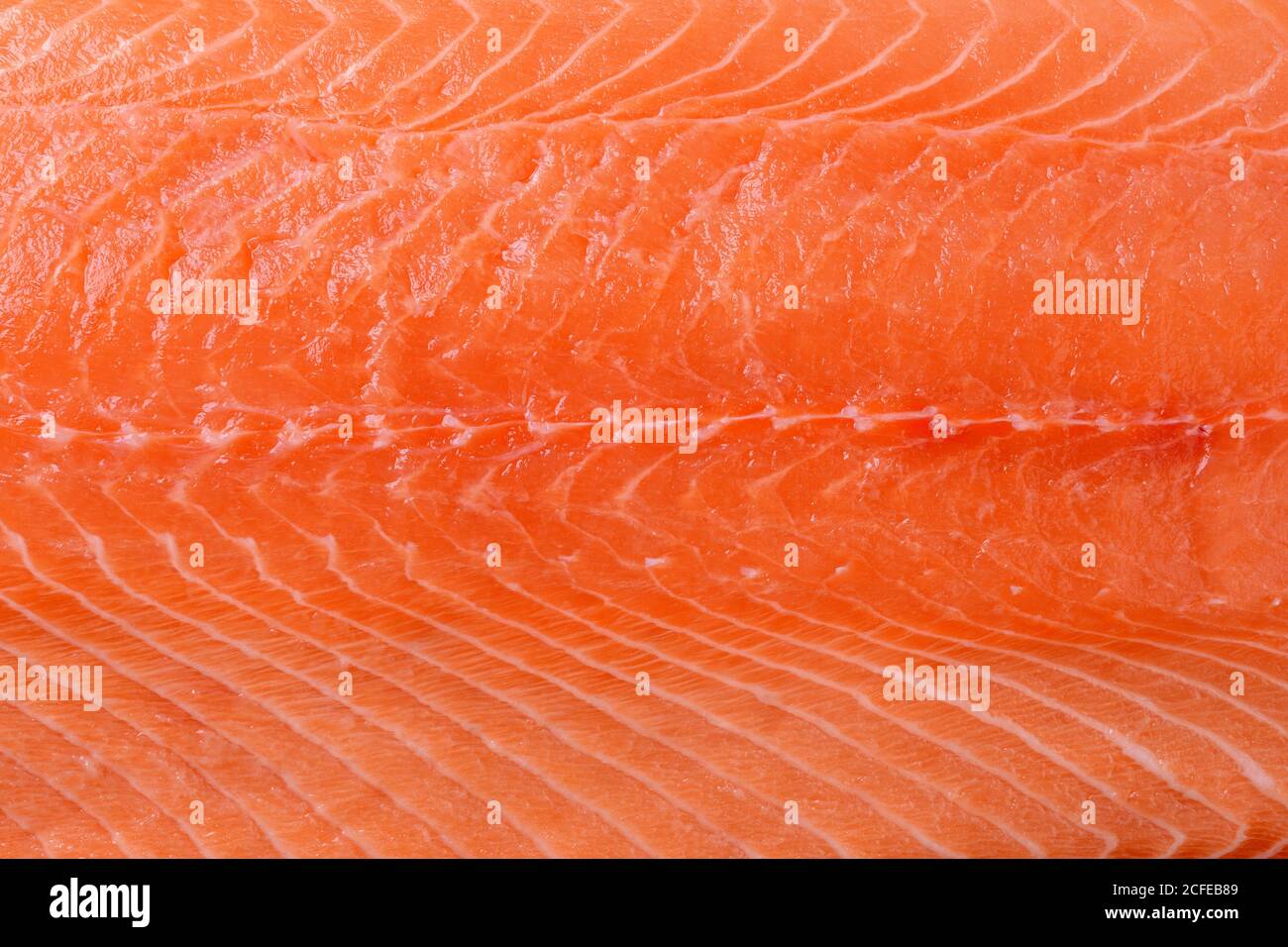 Filete de salmón crudo de fondo. Superficie de carne de salmón deshuesada fresca y refrigerada. Elemento de diseño para una alimentación saludable, ingrediente de recetas de marisco. Foto de stock