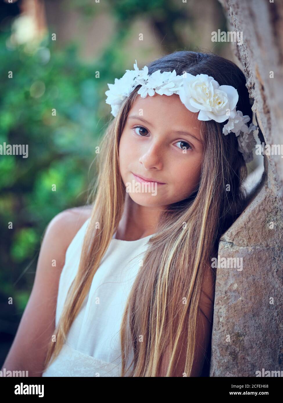 Ambientalista Romance archivo Retrato de una niña bonita con cinta blanca para la cabeza de la flor de la  ropa apoyándose en la pared y mirando la cámara Fotografía de stock - Alamy