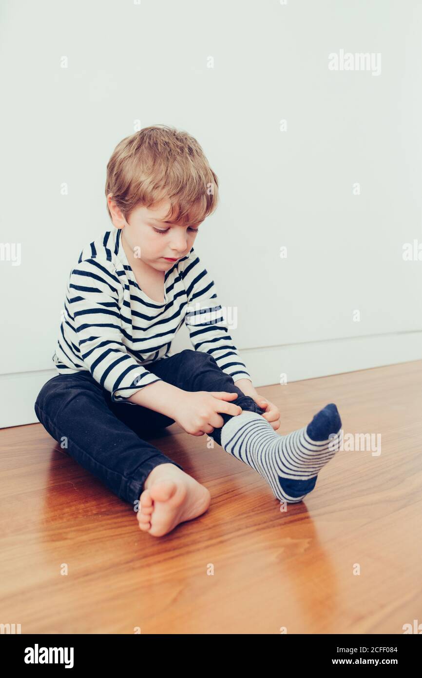 Niño divertido con calcetines y sentado en el suelo de la habitación  Fotografía de stock - Alamy