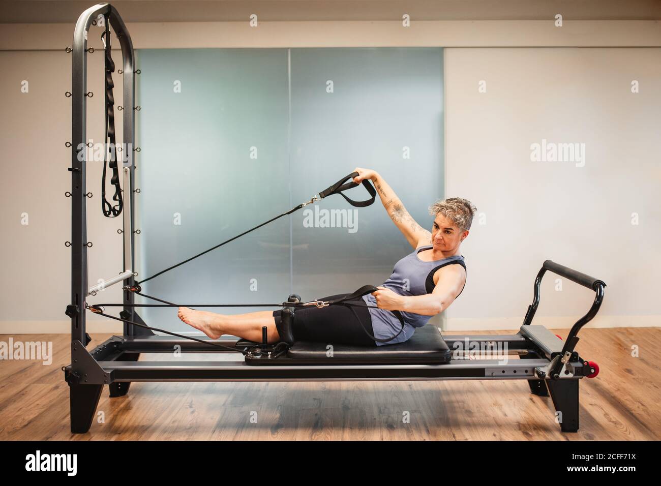 Vista lateral de la mujer adulta en ropa deportiva acostada en pilates  máquina y hacer ejercicios con bandas de resistencia Fotografía de stock -  Alamy