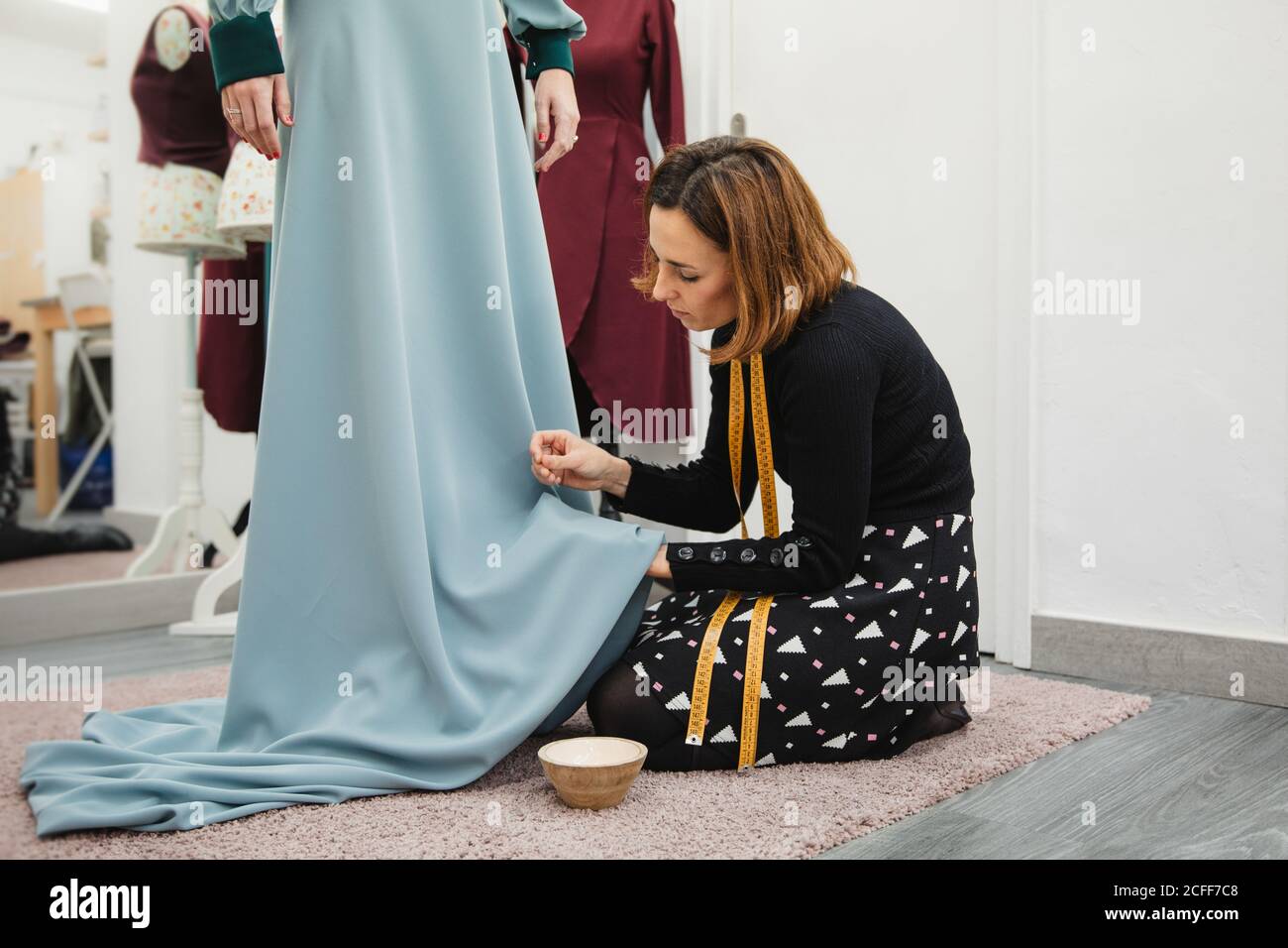 Tocador arrodillado sobre alfombra y falda de ajuste de bata personalizada mientras trabaja en un estudio profesional Foto de stock