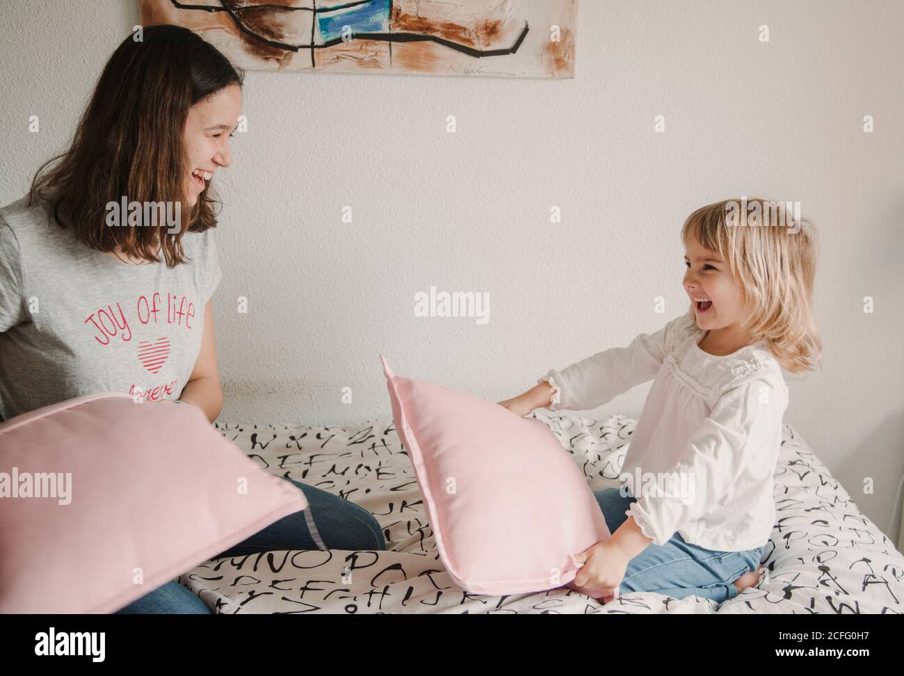 Vista lateral de adolescentes juguetones y niñas sentados cama acogedora y  divertirse durante la pelea de almohadas Fotografía de stock - Alamy