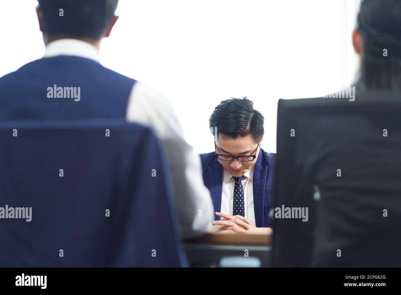 joven hombre de negocios asiático que se ve triste después de aprender la terminación de empleo Foto de stock