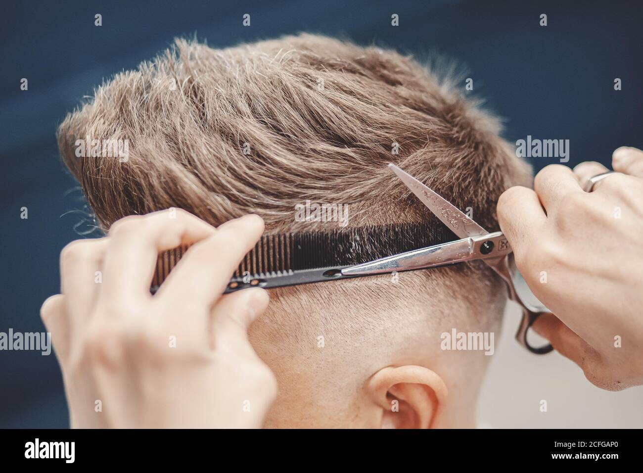 Peluquero usando tijeras y peine para cortar el cabello del hombre